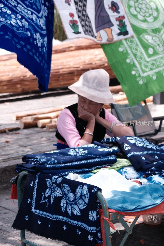 戴着帽子的妇女在摊前售卖蓝印花布