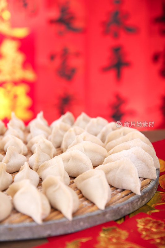 喜庆红色的背景前包好待煮的节日饺子