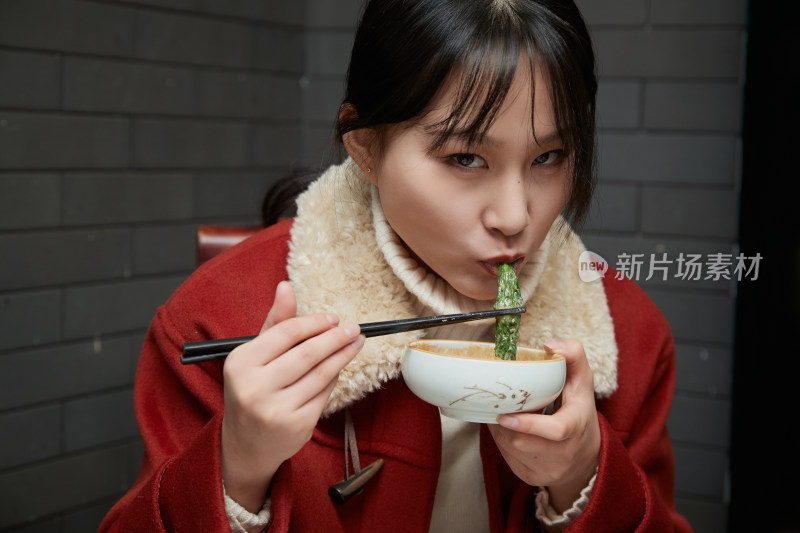 在饭店吃传统铜锅涮肉的亚洲少女