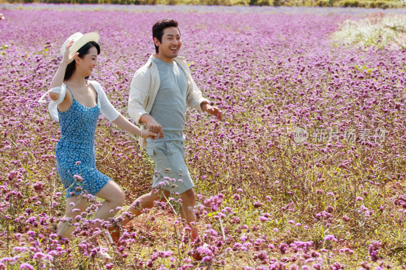 青年夫妇手牵手在花海里奔跑