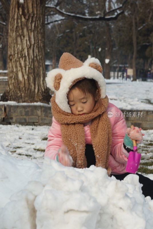 戴可爱帽子的小女孩在户外玩雪