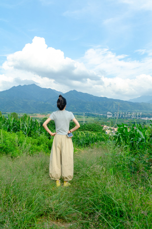 陕西秦岭山下，苗条女子于田野间眺望远山