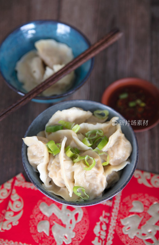 桌子上一碗饺子和蘸料红包及茶水