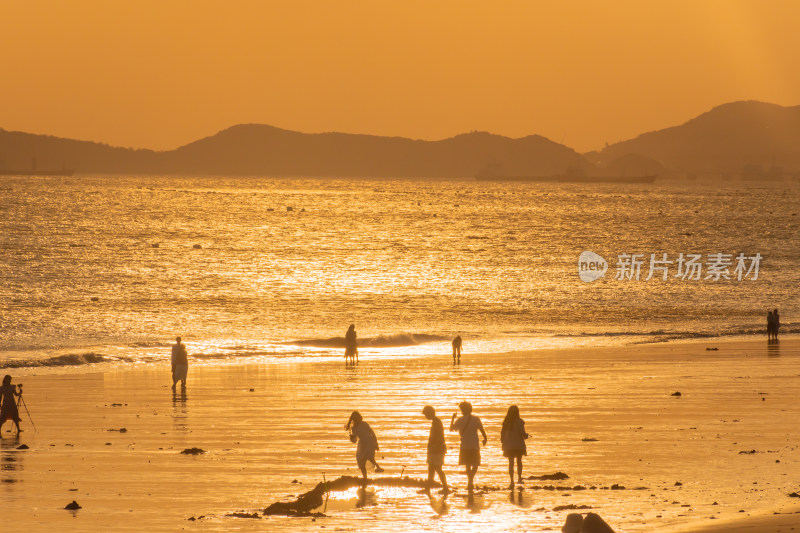 海边夕阳下的人群休闲场景