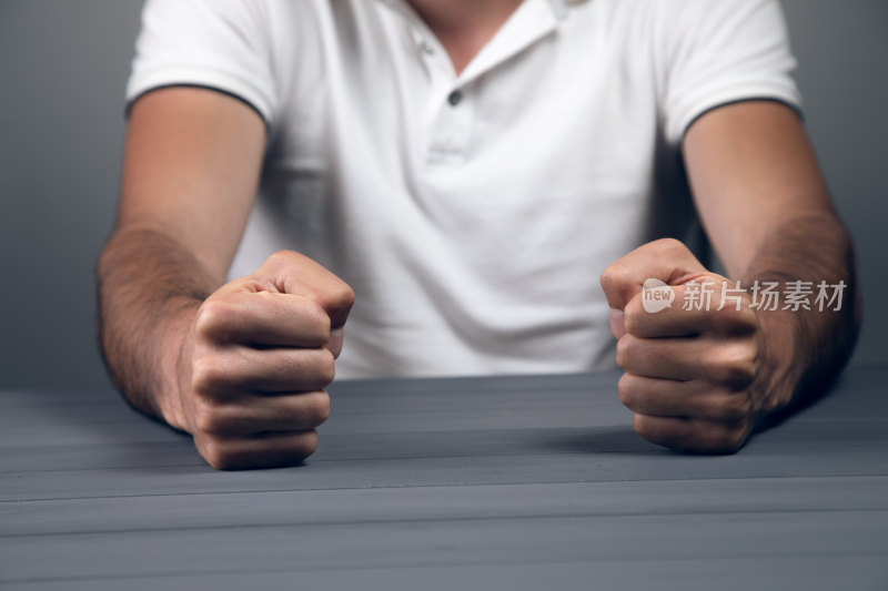 男性握拳置于桌面特写