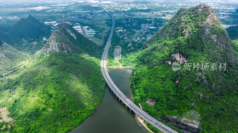 俯瞰阳光下桂林高山间湖泊上的高速公路大桥