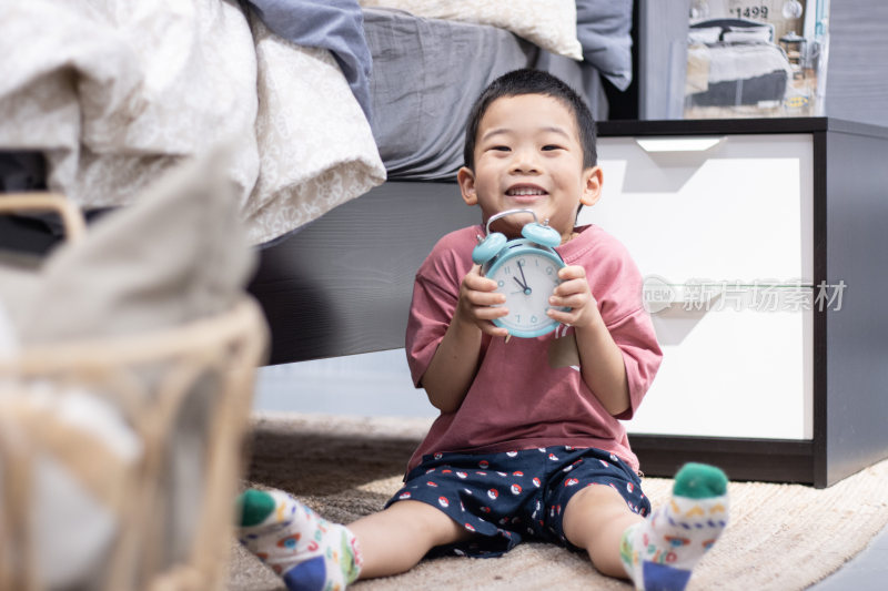 一个小男孩坐在地毯上玩闹钟