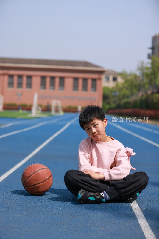 可爱的男孩坐在田径场上的肖像