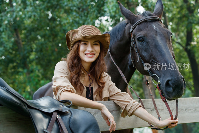 趴在围栏上的时尚个性女孩牵着马