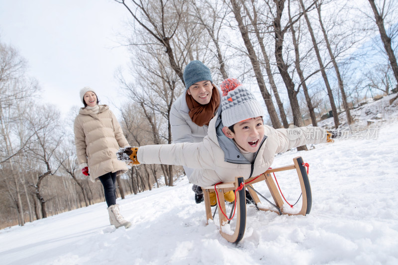 在雪地上玩雪橇的一家人