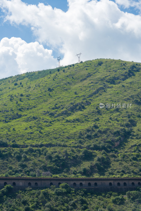 蓝天白云下的绿意盎然的山丘风景