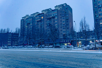 雪天夜晚亮灯的居民楼外景马路街道