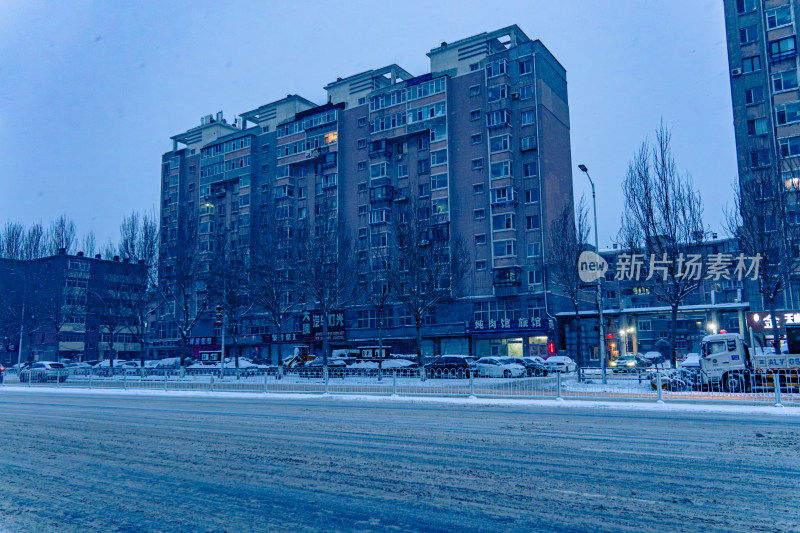 雪天夜晚亮灯的居民楼外景马路街道