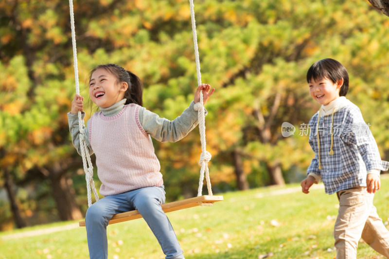 在公园里荡秋千的快乐儿童