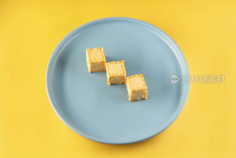 黄色背景中蓝色盘子里的鱼豆腐