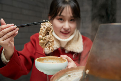 在饭店吃传统铜锅涮肉的亚洲少女