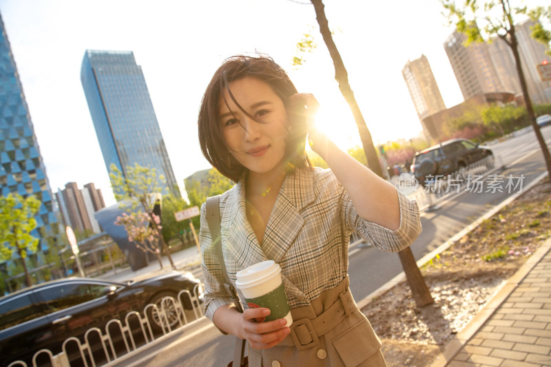 青年女人拿着饮料走在马路上