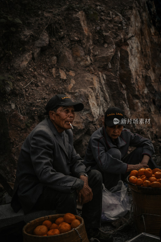 老街岩石旁卖水果的老人