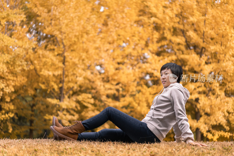 秋天坐在银杏树里草坪上中国女性