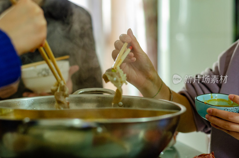 人们用筷子在锅中夹食物的用餐场景