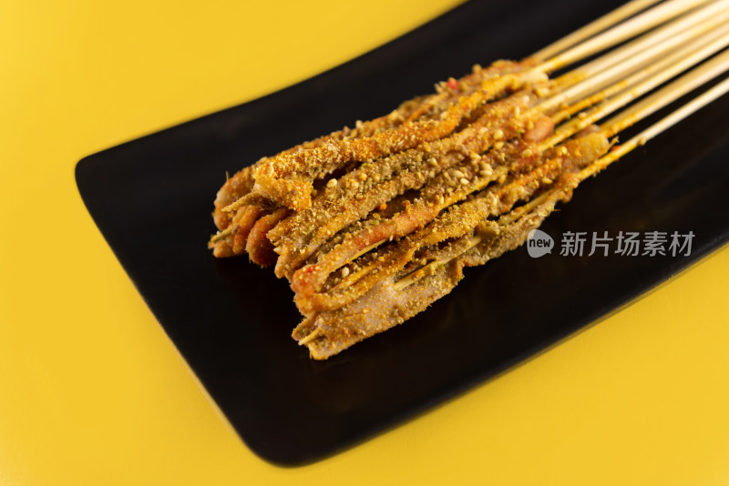 黄色背景中黑色盘子里的牛肉小串