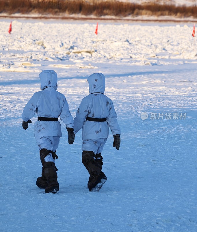 两人穿着冬装在雪地上牵手行走