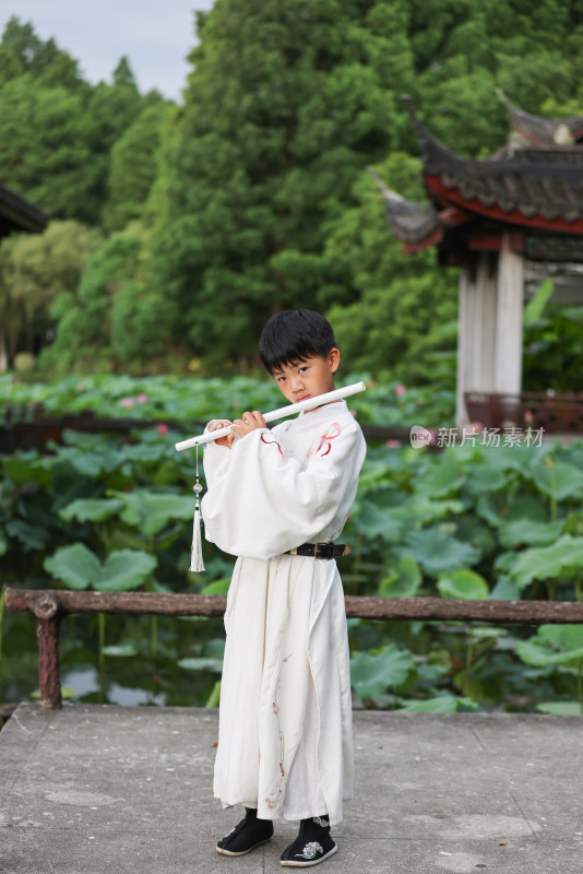 穿着汉服的男孩站在荷塘旁