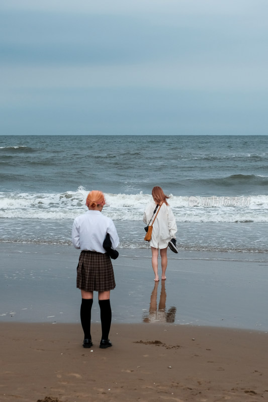 海边两位女子漫步的场景