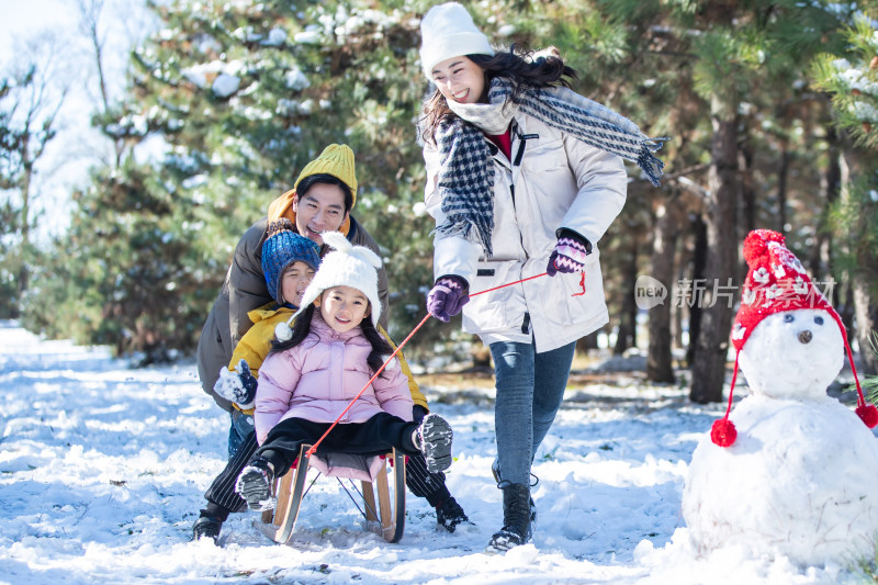 在雪地上玩雪橇的一家人