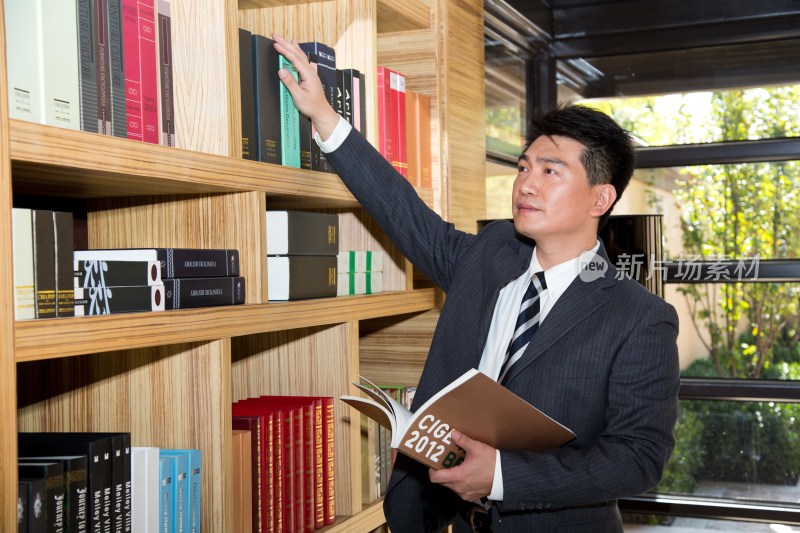 中年商务男士在书柜前看书