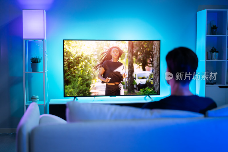 男子在家沙发上观看电视节目