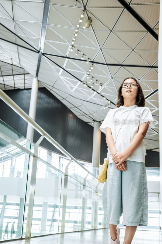 戴眼镜女孩在现代建筑内行走参观