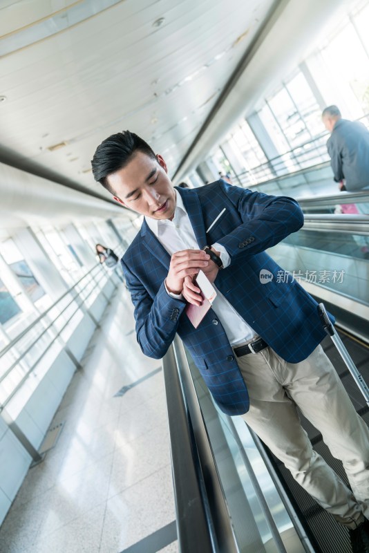 年轻商务人士在机场乘坐移动电梯
