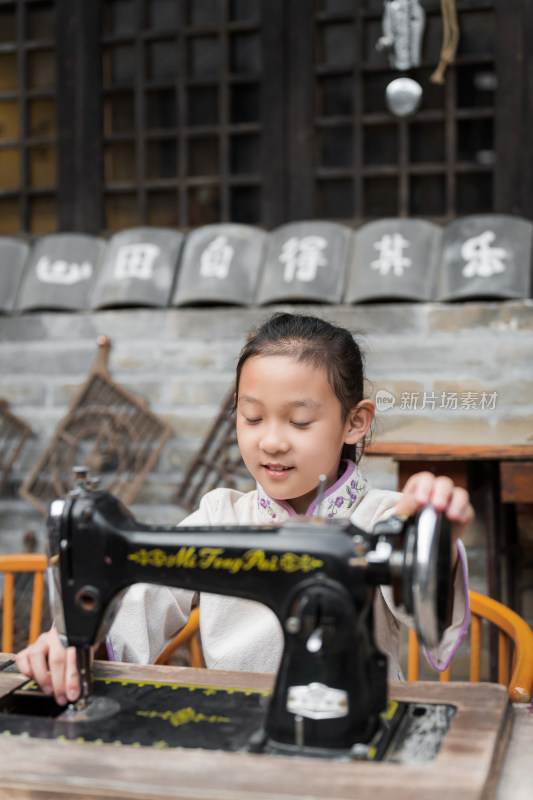 坐在中式庭院中学习使用老式缝纫机的女孩