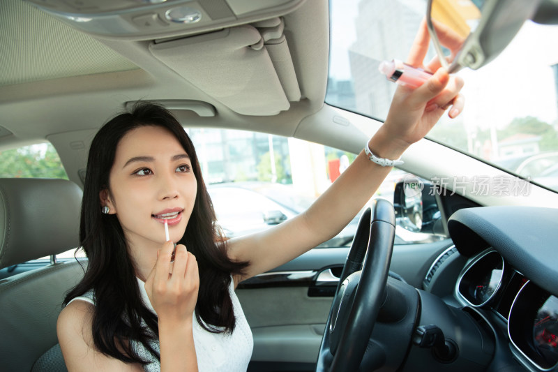 漂亮的青年女人对着后视镜化妆