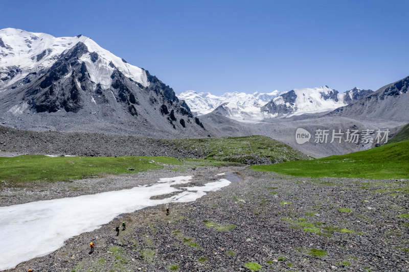 徒步者在穿越新疆天山山脉的雪山与草原