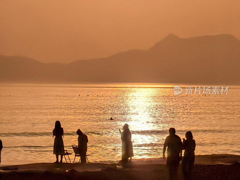 海边夕阳下的人群剪影