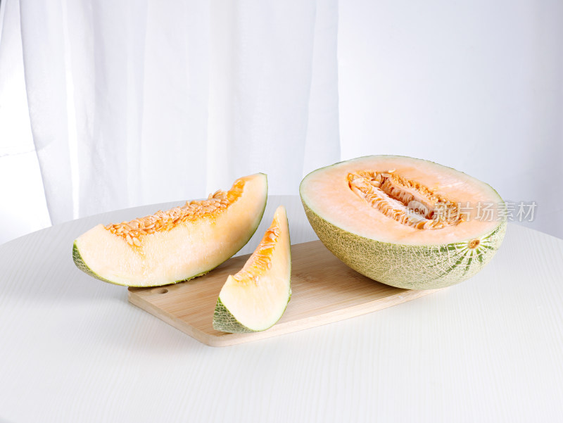 白色桌面上摆放着切开的新鲜水果哈密瓜
