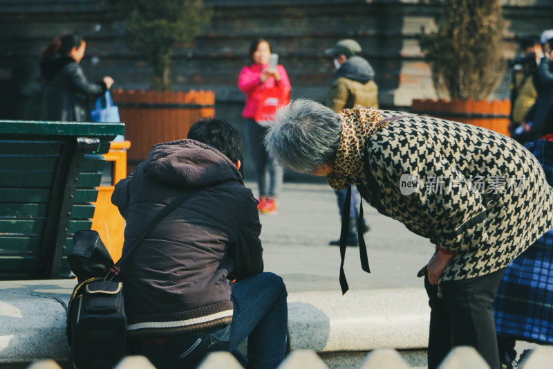 户外公共场，老人好奇的看着男人给别人拍摄