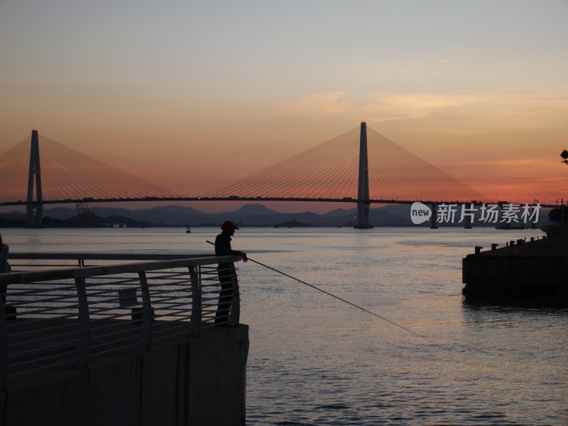 黄昏江边男子倚栏垂钓