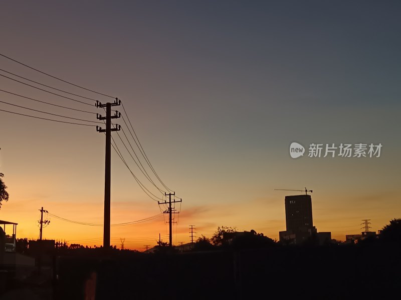 夕阳下的电线杆与城市高楼剪影