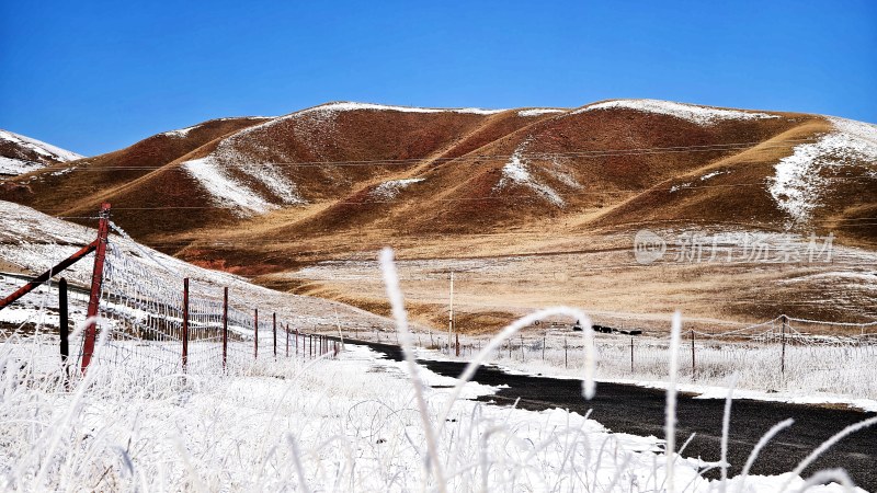 覆雪山路旁是棕白相间的山坡