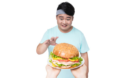 肥胖的年轻男子在看汉堡