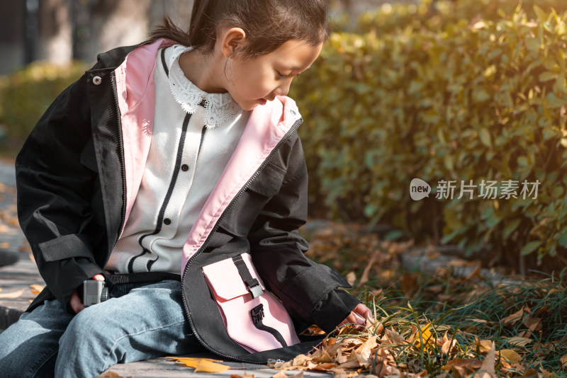秋天坐在树下玩耍的中国女孩