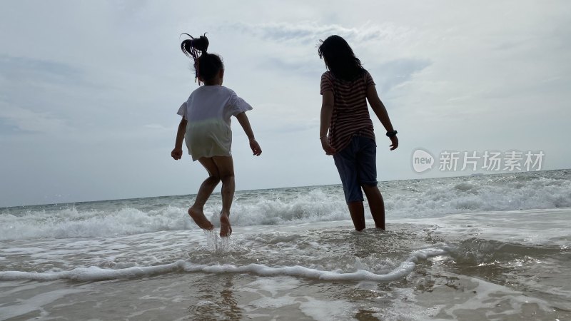 母女海边踏浪玩耍背影