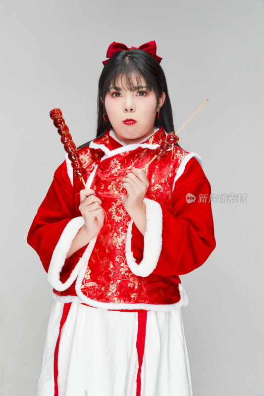 身穿喜庆服饰手拿糖葫芦吃的可爱亚洲少女
