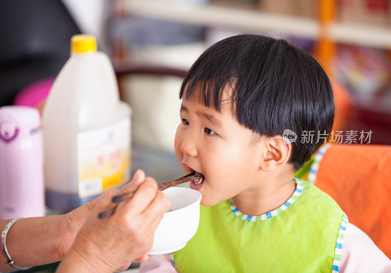 正在给亚洲面孔的小女孩喂饭