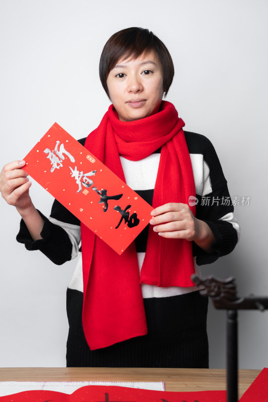 在白色背景前展示春联的中国女性
