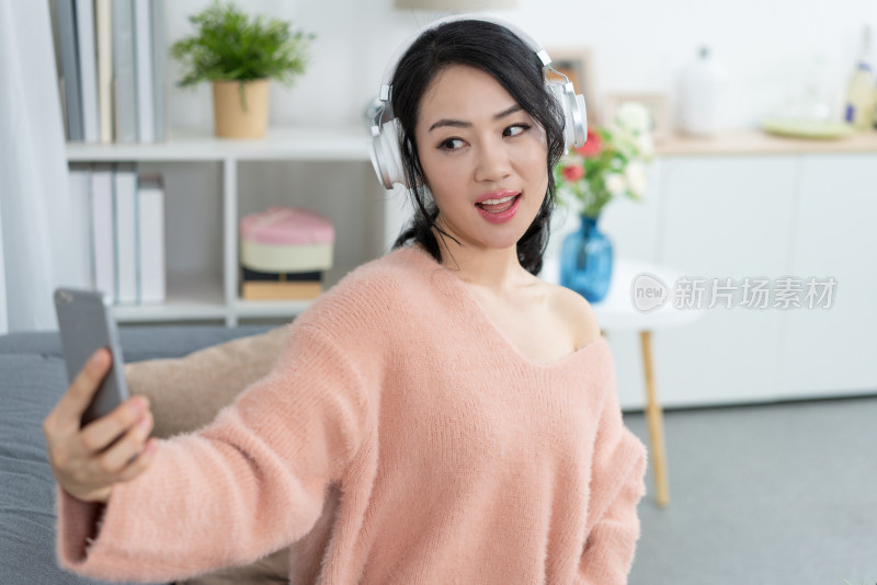 年轻女子坐在沙发上听音乐