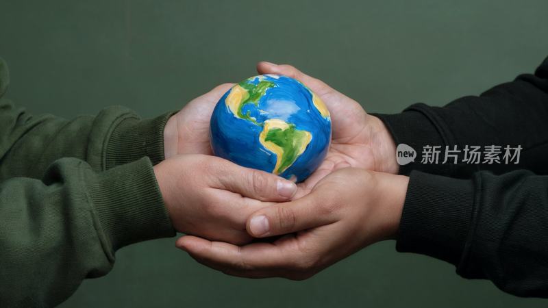 两人双手捧着地球模型的场景